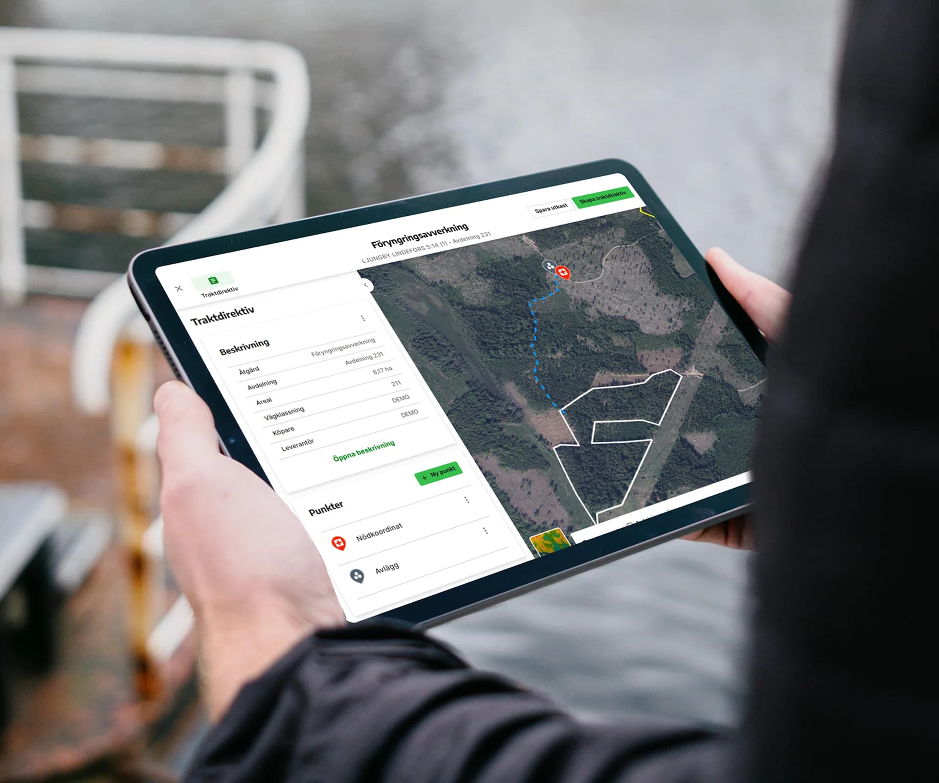 En person håller i en iPad som visar ett traktdirektiv med en karta och beskrivning i Skogshubbens.